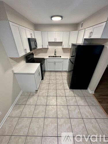 A kitchen with white cabinets and black appliances.
