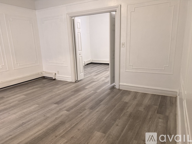 A room with wooden flooring and white walls.