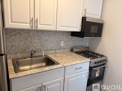 A kitchen with a stove, sink, and cabinets.