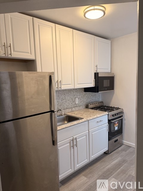 A kitchen with white cabinets and a stainless steel refrigerator.