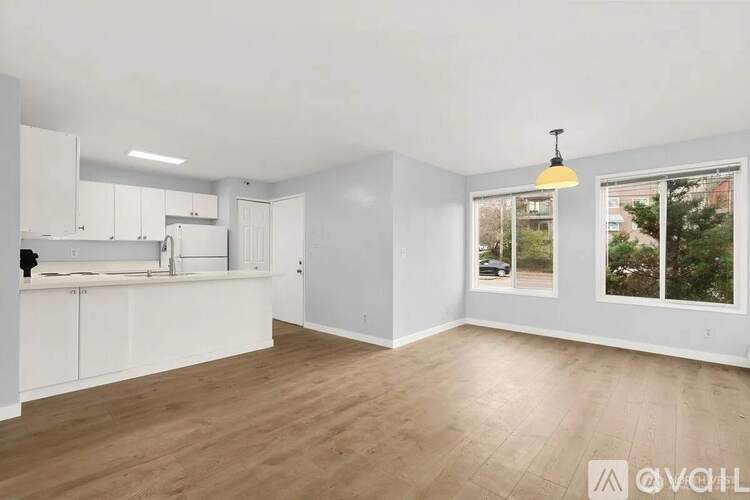 A spacious room with wooden flooring and white walls.