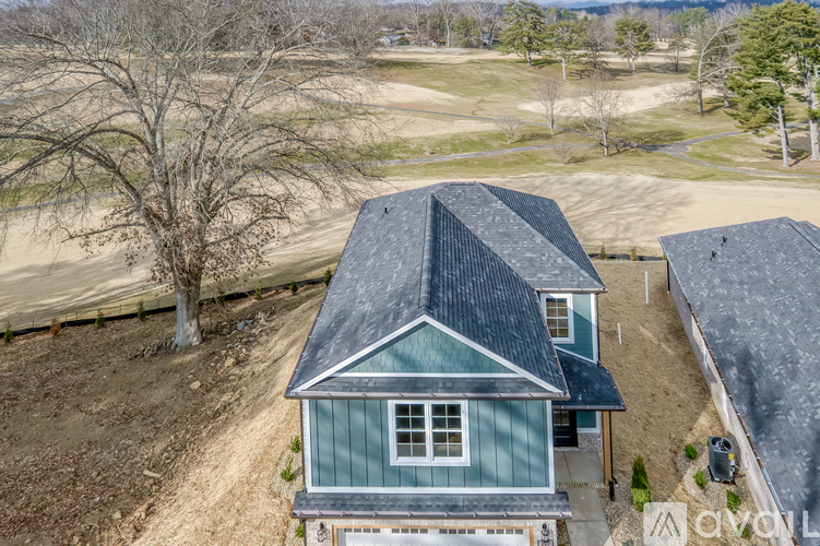 A house with a grey roof is surrounded by a dirt field.