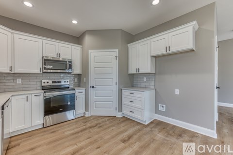 A kitchen with white cabinets and a wooden floor.