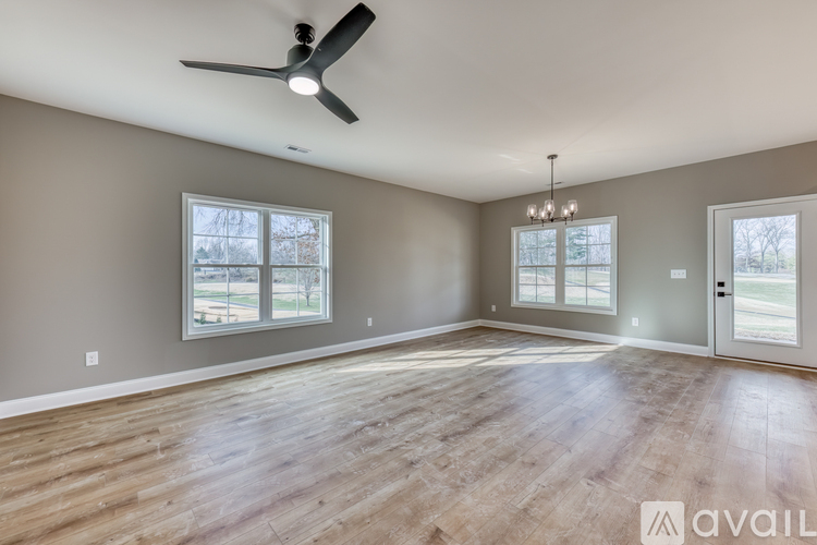 A spacious room with a ceiling fan and wooden flooring.