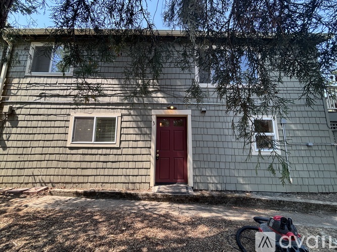 A house with a red door and a tree branch hanging on the wall.
