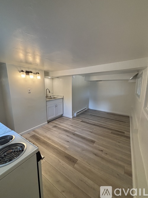 A kitchen with a stove top oven and wooden flooring.