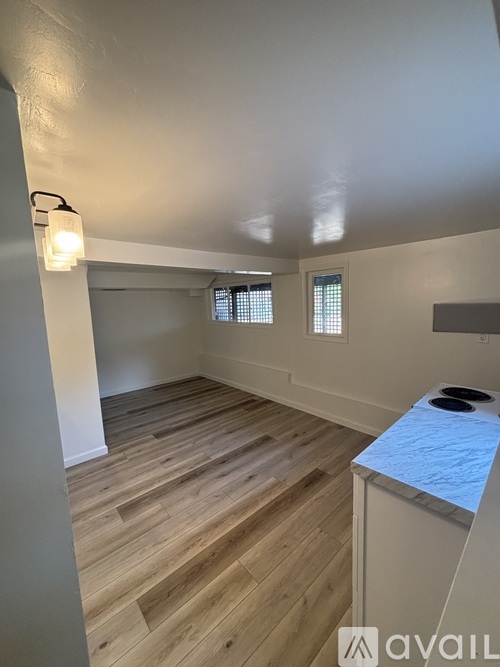 A room with wooden floors and a window with blinds.
