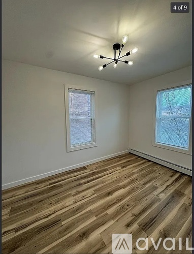 A room with wooden flooring and a window with a view of trees.