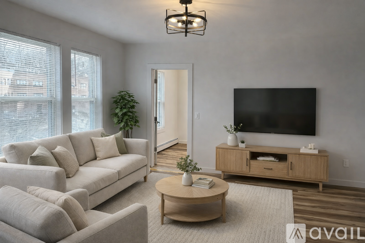 A living room with a large couch, a coffee table, and a flat-screen TV.