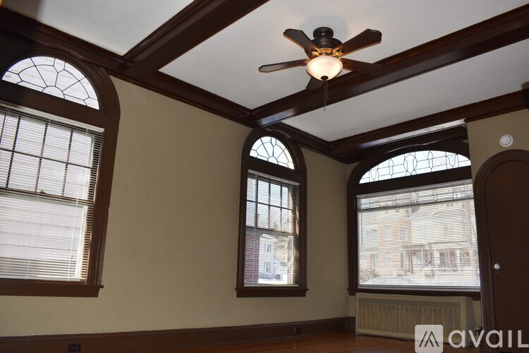 A room with a ceiling fan and three windows.