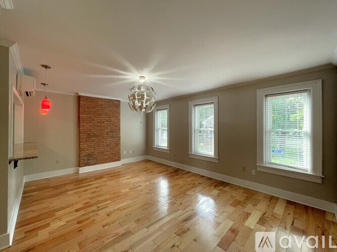 A room with wooden flooring and a chandelier hanging from the ceiling.