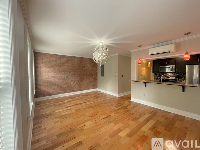 A room with wooden flooring and a brick wall.