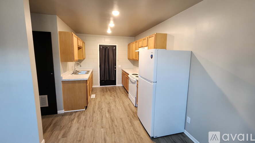 A kitchen with a white refrigerator and wooden cabinets.