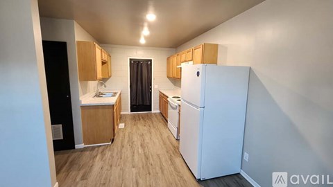 A kitchen with a white refrigerator and wooden cabinets.
