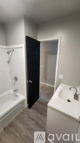 A bathroom with a black door and a white sink.