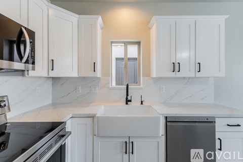 A kitchen with white cabinets and a marble countertop.