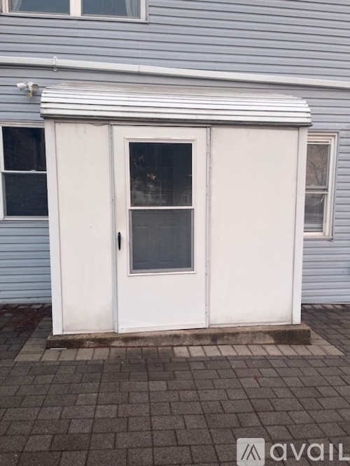 A white door with a window is on a grey house.