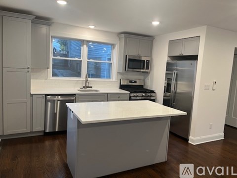 A modern kitchen with a white island and stainless steel appliances.
