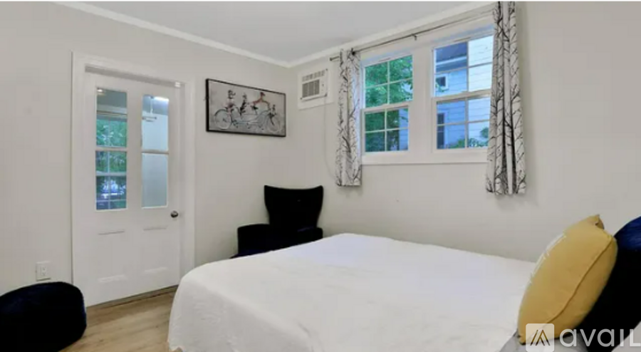 A bedroom with a bed, chair, and window.