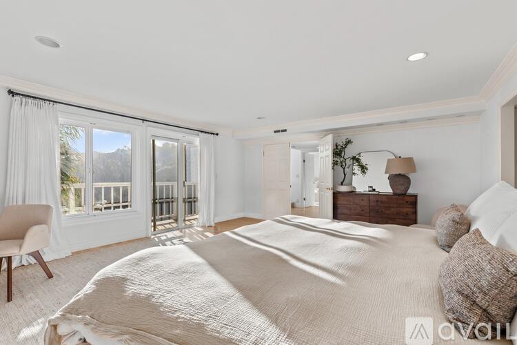 A bedroom with a large bed and a chair by the window.
