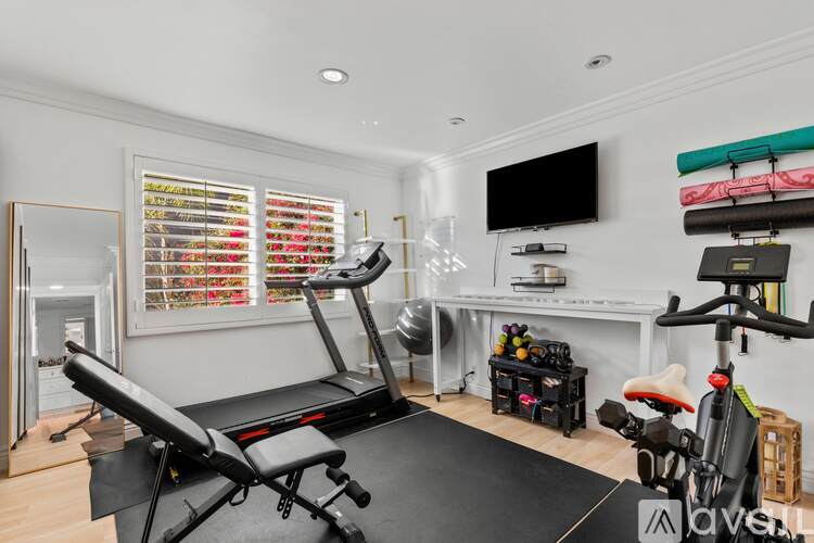 A home gym with a treadmill, exercise bike, and other equipment.