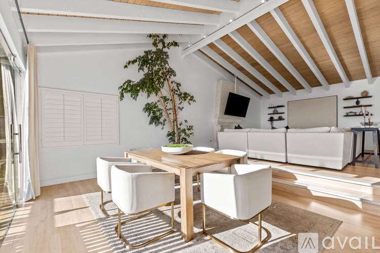 A dining area with a table and chairs and a tree in the corner.