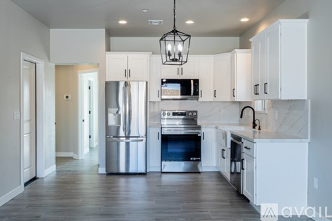 A modern kitchen with white cabinets and stainless steel appliances.