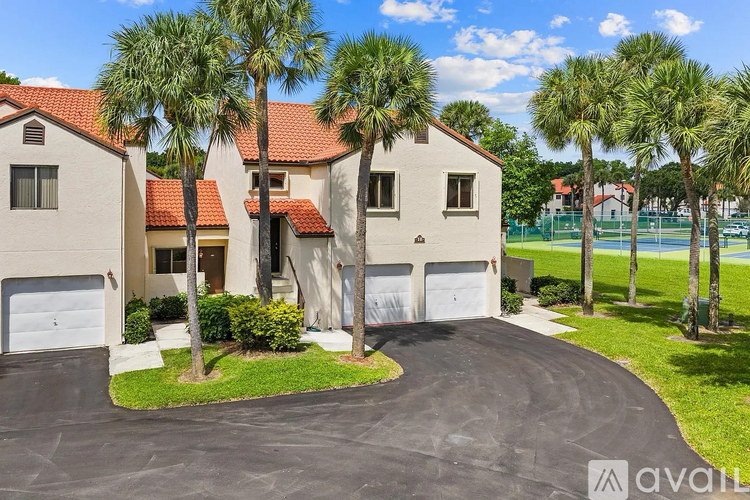 A house with a driveway and palm trees in front.