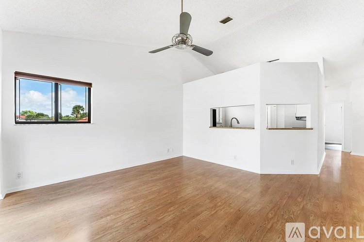 A spacious room with wooden floors and a ceiling fan.