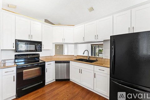 A kitchen with white cabinets and a black refrigerator.