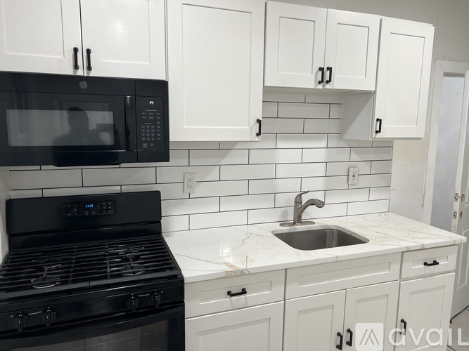 A kitchen with black appliances and white cabinets.