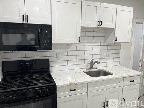A kitchen with black appliances and white cabinets.