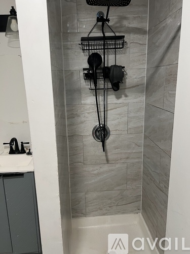 A shower with a black hose and a black shower head.