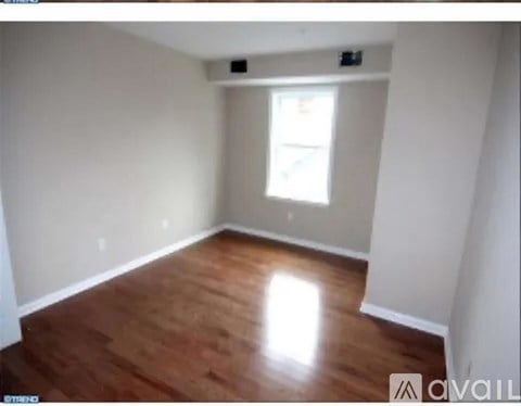 Empty room with wooden flooring and a window.