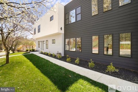 A modern house with a white and grey exterior and a green lawn in front.