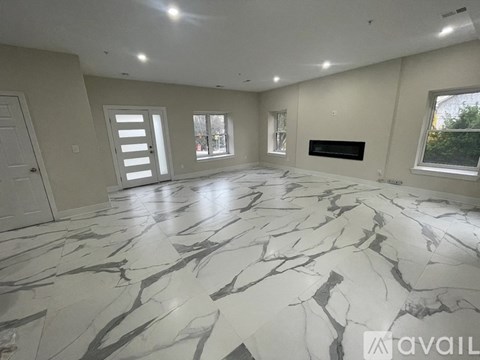 A spacious room with marble flooring and a fireplace.