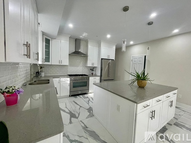 A kitchen with white cabinets and a marble countertop.