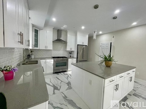 A kitchen with white cabinets and a marble countertop.