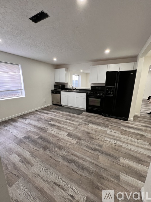 A kitchen with black appliances and wooden flooring.
