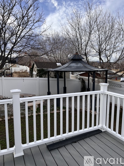 A gazebo sits on a wooden deck with a white railing.