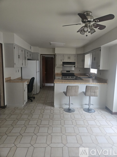 A kitchen with a white tile floor and a ceiling fan.