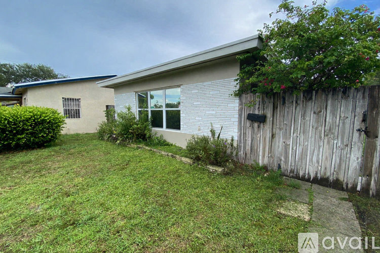 A house with a fence and a bush in front of it.