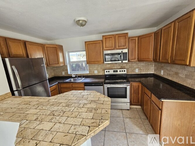 A kitchen with wooden cabinets and a stone countertop.