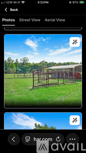 A photo of a grassy field with a fence and a building in the background.