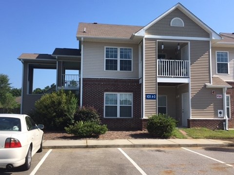 A two-story apartment building with a car parked in front.