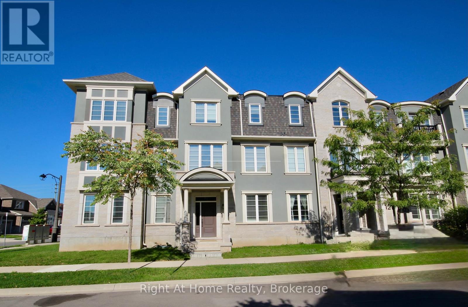 A large, multi-story house with a grey and white exterior and multiple windows.