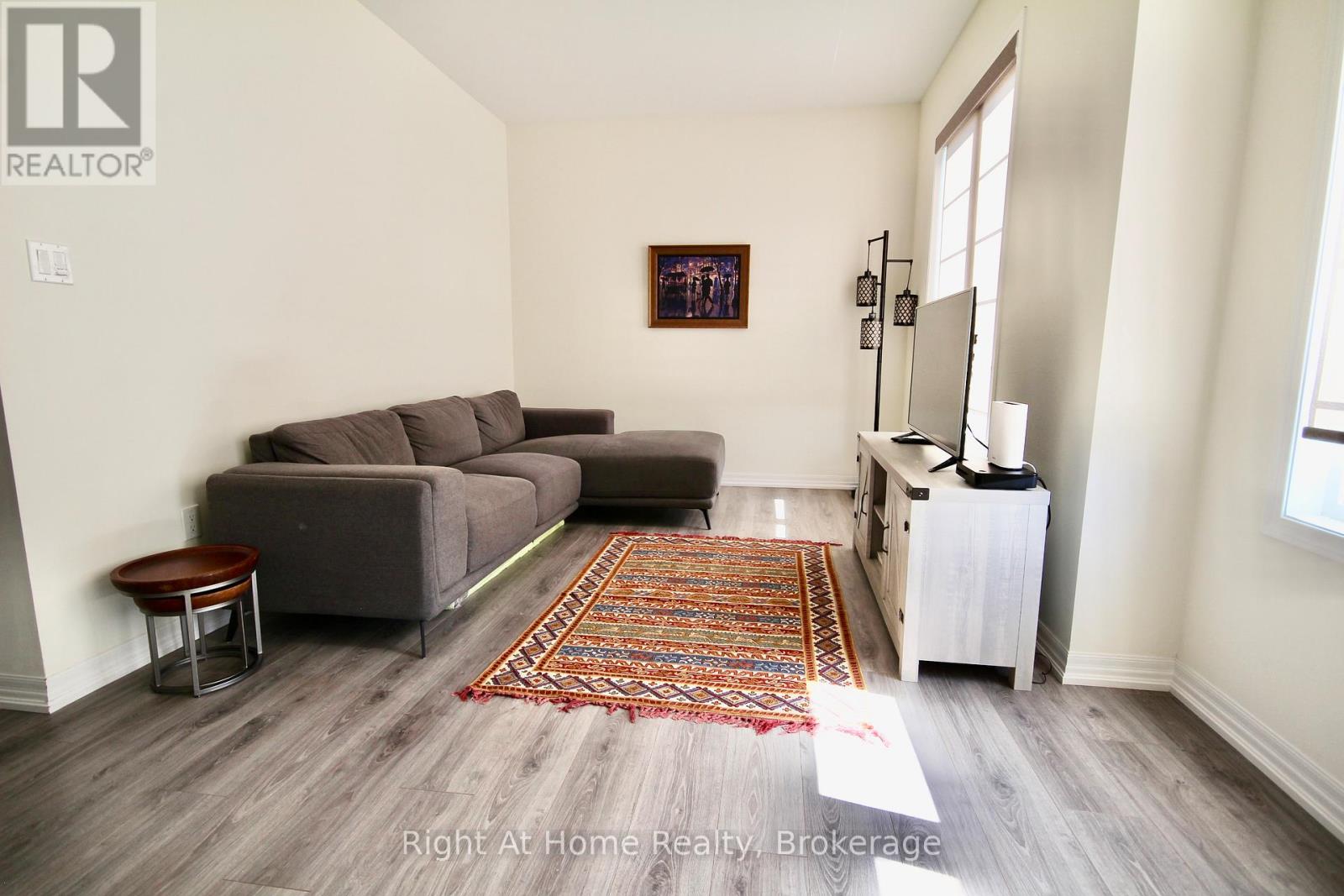 A living room with a grey couch and a rug on the floor.