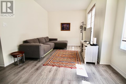 A living room with a grey couch and a rug on the floor.