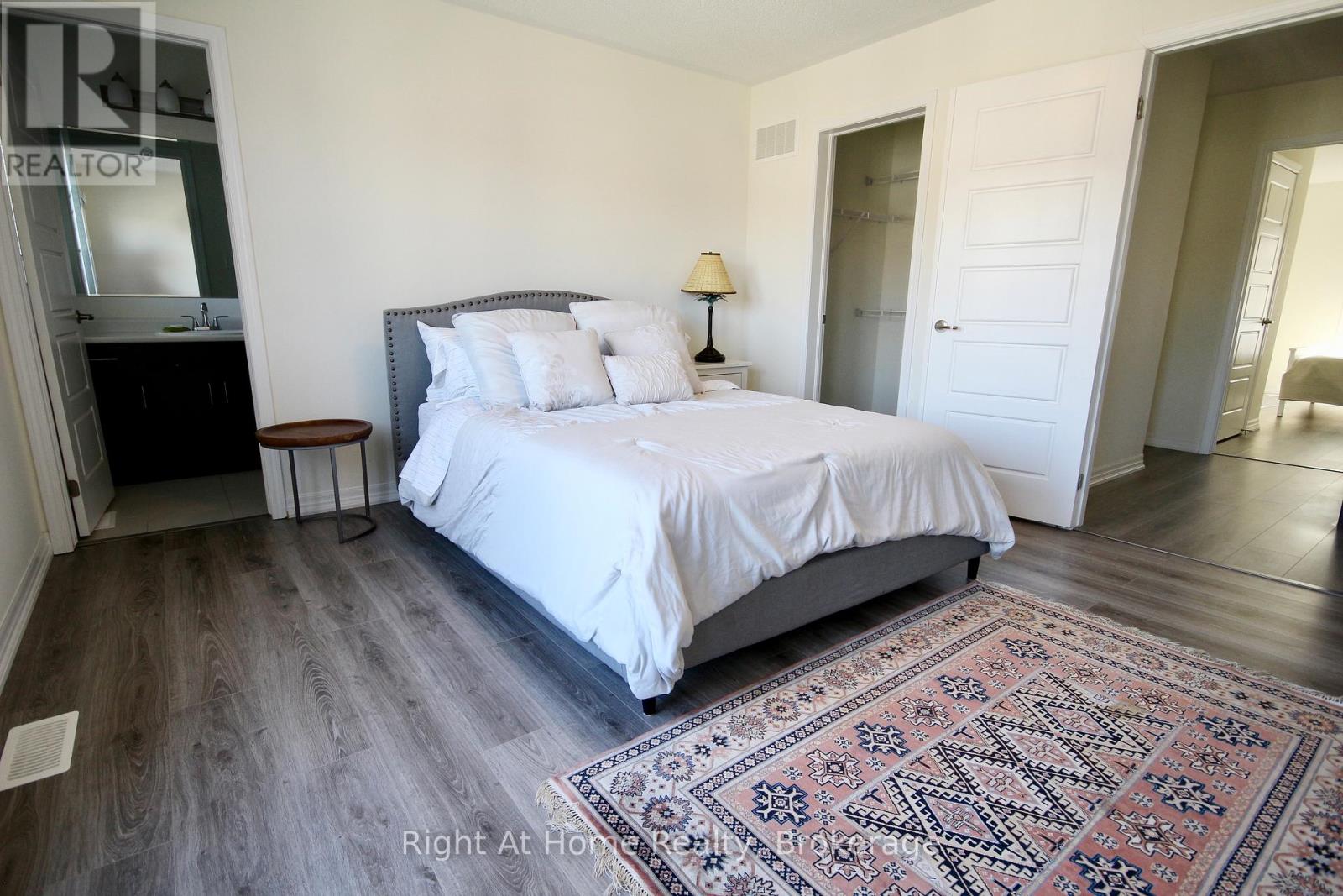 A bedroom with a large bed and a rug on the floor.