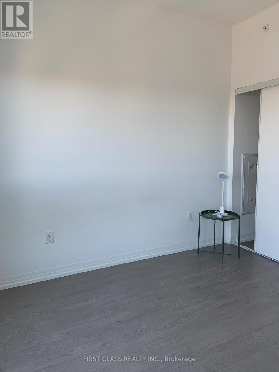 A room with a grey floor and a white wall with a small table and a candle on it.